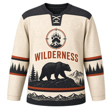 Load image into Gallery viewer, Black Bear Wilderness Original Hockey Jersey in Birch Cream, front view – black bear on a rocky ridge with pines and paw-print crest, custom name and number