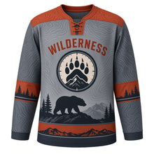 Load image into Gallery viewer, Black Bear Wilderness Original Hockey Jersey in Slate Ridge, front view – black bear on a rocky ridge with pines and paw-print crest, custom name and number