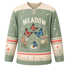 Load image into Gallery viewer, Butterfly Meadow Original Hockey Jersey in Sage Garden, front view – three butterflies over a wildflower meadow and butterfly-on-daisy crest, custom name and number
