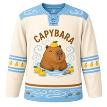 Load image into Gallery viewer, Capybara Hot Spring Original Hockey Jersey in Yuzu Cream, front view – relaxed capybara soaking in a steaming hot spring with yuzu fruits and capybara crest, custom name and number