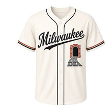 Load image into Gallery viewer, Cobblestone Alley Milwaukee Baseball Jersey in Mortar Cream, front view – cobblestone lane and arched brick doorway graphic with keystone crest, custom name and number