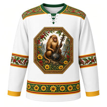 Load image into Gallery viewer, Ethiopia Original Hockey Jersey in Shemma White, front view – ornate tibeb-framed crest with a Simien gelada, jebena coffee pot, coffee cherries and adey abeba daisies, tibeb-weave yoke, detailed artwork, custom name and number
