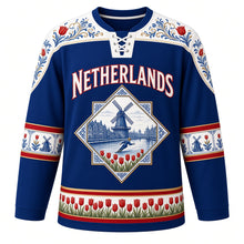 Load image into Gallery viewer, Netherlands Original Hockey Jersey in Delft Blue, front view – NETHERLANDS chest lettering, Hindeloopen-painted yoke and Delft-tile windmill crest in ornate detailed artwork, custom name and number