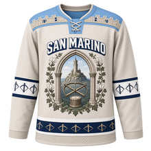 Load image into Gallery viewer, San Marino Original Hockey Jersey in Titano Stone, front view – battlement-stone yoke and gothic-arch Mount Titano tower crest with ornate detailed artwork, custom name and number