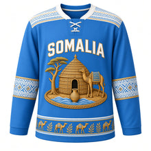 Load image into Gallery viewer, Somalia Original Hockey Jersey in Benadir Royal Blue, front view – alindi-stripe yoke and aqal-dome crest with camel, frankincense tree and dhiil vessel, ornate detailed artwork, custom name and number