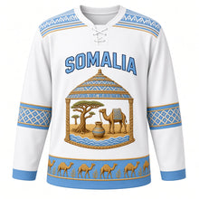 Load image into Gallery viewer, Somalia Original Hockey Jersey in Coastal White, front view – alindi-stripe yoke and aqal-dome crest with camel, frankincense tree and dhiil vessel, ornate detailed artwork, custom name and number