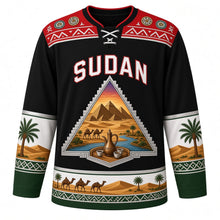 Load image into Gallery viewer, Sudan Original Hockey Jersey in Meroe Black, front view – ornate pyramid-shaped crest with Meroe pyramids, camel caravan and Nile confluence, Nubian painted yoke, detailed artwork, custom name and number