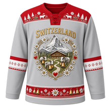 Load image into Gallery viewer, Switzerland Original Hockey Jersey in Edelweiss Silver, front view – ornate heart-shaped papercut crest with Matterhorn, chalet, cowbells and alphorns, detailed artwork, custom name and number
