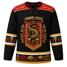 Load image into Gallery viewer, Timor-Leste Original Hockey Jersey in Ikat Black, front view – ornate tais-banner crest with the legendary crocodile island, coffee branches and babadok drums, detailed artwork, custom name and number