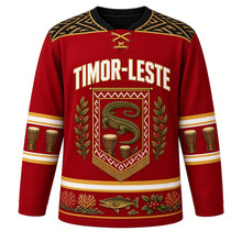 Load image into Gallery viewer, Timor-Leste Original Hockey Jersey in Tais Red, front view – ornate tais-banner crest with the legendary crocodile island, coffee branches and babadok drums, detailed artwork, custom name and number