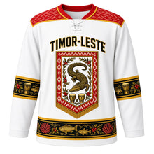 Load image into Gallery viewer, Timor-Leste Original Hockey Jersey in Atauro White, front view – ornate tais-banner crest with the legendary crocodile island, coffee branches and babadok drums, detailed artwork, custom name and number