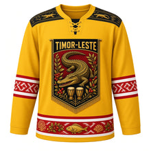 Load image into Gallery viewer, Timor-Leste Original Hockey Jersey in Coffee Blossom Yellow, front view – ornate tais-banner crest with the legendary crocodile island, coffee branches and babadok drums, detailed artwork, custom name and number