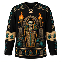 Load image into Gallery viewer, Ugly Halloween Mummy Tomb Crawl Hockey Jersey in Midnight Black, front view – midnight black body with sand yoke with a glowing-eyed bandaged mummy rising from an open sarcophagus with tomb torches and scarab beetles, hieroglyph-style yoke, bandage sleeve bands and a scarab hem band – custom name and number