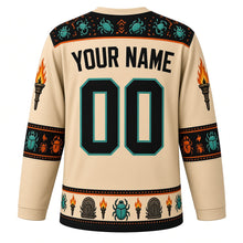 Load image into Gallery viewer, Ugly Halloween Mummy Tomb Crawl Hockey Jersey in Tomb Sand, back view with a hieroglyph-style yoke, bandage-stripe sleeve bands, scarab hem band, arched YOUR NAME lettering and 00 – custom name and number