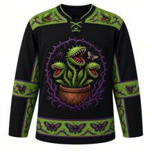 Load image into Gallery viewer, Ugly Halloween Carnivorous Plant Garden Hockey Jersey in Midnight Black, front view – midnight black body with poison green and purple trim with a crest of snapping carnivorous flytrap plants with jagged teeth and glowing eyes in a clay pot ringed by thorny vines, a spider and a moth, flytrap-and-thorn yoke and moth-patterned stripe bands – custom name and number
