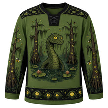 Load image into Gallery viewer, Ugly Halloween Swamp Creature Bayou Hockey Jersey in Swamp Green, front view – swamp green body with a scaly swamp creature with glowing eyes rising from a murky bayou crest with moss-draped cypress trees, lily pads, fireflies and bubbles, moss yoke, lily pad sleeve bands and a cypress tree hem band – custom name and number