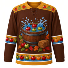 Load image into Gallery viewer, Ugly Thanksgiving Apple Bobbing Barrel Hockey Jersey in Barrel Brown, front view – barrel brown body with cider gold yoke, a wooden barrel tub of water with red and green apples splashing, hay bales, apples and oak leaves around the base, a yoke of apples floating on water ripples and sleeve and hem bands of apples floating on blue water with droplets – custom name and number