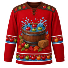 Load image into Gallery viewer, Ugly Thanksgiving Apple Bobbing Barrel Hockey Jersey in Apple Red, front view – apple red body with barrel brown yoke, a wooden barrel tub of water with red and green apples splashing, hay bales, apples and oak leaves around the base, a yoke of apples floating on water ripples and sleeve and hem bands of apples floating on blue water with droplets – custom name and number