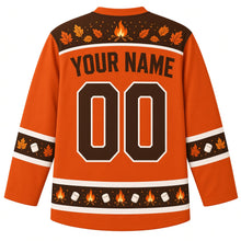Load image into Gallery viewer, Ugly Thanksgiving Autumn Bonfire Night Hockey Jersey in Ember Orange, back view with a brown yoke of a campfire, sparks and autumn leaves, marshmallow and leaf sleeve bands, a hem of mini campfires and marshmallows, YOUR NAME lettering and 00 – custom name and number