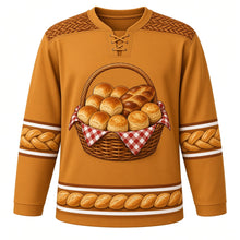 Load image into Gallery viewer, Ugly Thanksgiving Harvest Bread Basket Hockey Jersey in Golden Crust, front view – golden crust body with cinnamon brown yoke with a round crest of an overflowing woven wicker basket lined with red gingham and piled with golden dinner rolls, a braided loaf and flaky biscuits, basket-weave yoke, biscuit and braided-twist sleeve bands and a mini bread-basket hem band – custom name and number