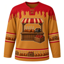 Load image into Gallery viewer, Ugly Thanksgiving Caramel Apple Stand Hockey Jersey in Caramel Gold, front view – caramel gold body with candy apple red yoke with a round crest of a rustic wooden farm stand with a striped awning and a counter of glossy caramel apples on sticks, a crate of apples and a caramel pot, caramel-drip yoke, caramel-apple sleeve bands and a caramel-apple-and-crate hem band – custom name and number