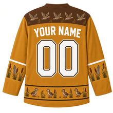 Load image into Gallery viewer, Ugly Thanksgiving Goose Flock Migration Hockey Jersey in Prairie Gold, back view – prairie gold body with marsh brown yoke with a row of five flying geese and little cattails, cattail-and-feather sleeve bands, a hem band of goslings among cattails, straight YOUR NAME lettering and 00 – custom name and number