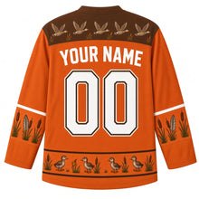 Load image into Gallery viewer, Ugly Thanksgiving Goose Flock Migration Hockey Jersey in Rust Orange, back view – rust orange body with marsh brown yoke with a row of five flying geese and little cattails, cattail-and-feather sleeve bands, a hem band of goslings among cattails, straight YOUR NAME lettering and 00 – custom name and number
