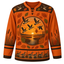 Load image into Gallery viewer, Ugly Thanksgiving Goose Flock Migration Hockey Jersey in Rust Orange, front view – rust orange body with marsh brown yoke, a round sunset marsh crest with five flying geese ringed by oak and oval leaves, a yoke with two flying geese and leaves, cattails on the sleeves and a hem band of geese waddling among cattails at the water – custom name and number