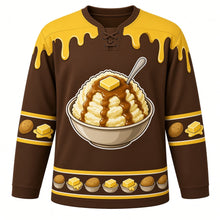 Load image into Gallery viewer, Ugly Thanksgiving Mashed Potato Mountain Hockey Jersey in Gravy Brown, front view – gravy brown body with butter yellow yoke with a round crest of a towering heap of mashed potatoes in a big bowl with a melting butter pat on top and a brown gravy river flowing down its slopes, a spoon planted in the peak, butter-and-gravy-drip yoke, potato and butter-pat sleeve bands and a mini potato-bowl hem band – custom name and number