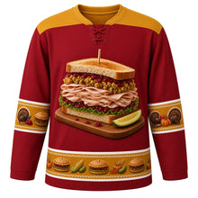 Load image into Gallery viewer, Ugly Thanksgiving Leftover Sandwich Stack Hockey Jersey in Cranberry Red, front view – cranberry red body with mustard gold yoke with a towering leftover sandwich on a wooden cutting board with sliced roast turkey, stuffing, cranberry sauce and lettuce between toasted bread slices, a wooden toothpick and a pickle wedge, roast turkey, mini-sandwich and pumpkin sleeve bands and a mini-sandwich, corn and pumpkin hem band – custom name and number