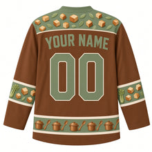 Load image into Gallery viewer, Ugly Thanksgiving Stuffing Stockpot Hockey Jersey in Cinnamon Brown, back view with a bread-cube and sage-leaf yoke, celery and bread-cube sleeve bands, a hem of mini stockpots and spoons, arched YOUR NAME lettering and 00 – custom name and number