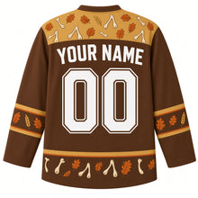 Load image into Gallery viewer, Ugly Thanksgiving Wishbone Wish Hockey Jersey in Cinnamon Brown, back view with scattered wishbones and oak leaves in the gold yoke and hem, leaf sleeve bands, YOUR NAME lettering and 00 – custom name and number