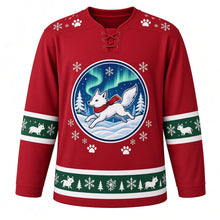 Load image into Gallery viewer, Ugly Christmas Arctic Fox Frolic Hockey Jersey in Cranberry Red, front view – cranberry red body with a round badge of a white arctic fox in a red scarf leaping through snow under green aurora lights with pines, paw-print and snowflake yoke and little-fox sleeve and hem bands – custom name and number