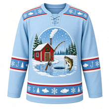 Load image into Gallery viewer, Ugly Christmas Ice Fishing Cabin Hockey Jersey in Frost Blue, front view – frost blue body with a fish-and-snowflake yoke with a round crest of a red ice-fishing shack with a wreath and smoking stovepipe on a frozen lake, a rod over an ice hole and a leaping fish among snowy pines, plus fish, hook, pine and snowflake bands – custom name and number