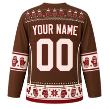 Load image into Gallery viewer, Ugly Christmas Mitten Clothesline Hockey Jersey in Cocoa Brown, back view with a hanging mitten yoke, cream mitten-pair sleeve bands, a cream hem band of clothespinned mittens with a red trim, cream YOUR NAME and 00 – your name and number