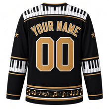 Load image into Gallery viewer, Ugly Christmas Piano Lounge Noel Hockey Jersey in Midnight Black, back view with a piano-key yoke, piano-key elbow bands, a gold music-note hem band and gold YOUR NAME and 00 – your name and number
