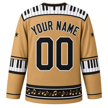 Load image into Gallery viewer, Ugly Christmas Piano Lounge Noel Hockey Jersey in Champagne Gold, back view with a piano-key yoke on champagne gold, piano-key elbow bands, a black music-note hem band and black YOUR NAME and 00 trimmed in white – your name and number
