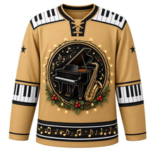 Load image into Gallery viewer, Ugly Christmas Piano Lounge Noel Hockey Jersey in Champagne Gold, front view – round crest of a black grand piano and a gold saxophone with gold music notes and holly, ringed by glowing string lights on a champagne gold body, piano-key yoke and elbow bands, black sleeve stars and a black music-note hem band – custom name and number