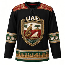 Load image into Gallery viewer, United Arab Emirates Original Hockey Jersey in Dune Night Black, front view – ornate Al Sadu shield crest with falcon, dhow and ghaf tree, detailed artwork, custom name and number