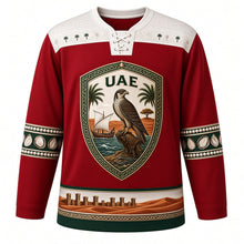 Load image into Gallery viewer, United Arab Emirates Original Hockey Jersey in Sadu Red, front view – ornate Al Sadu shield crest with falcon, dhow and ghaf tree, detailed artwork, custom name and number