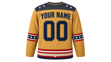 Load image into Gallery viewer, USA Patriotic Eagle and Flag Hockey Jersey in Prairie Gold, back view with your name and number – overlapping feather-pattern yoke with flag-stripe sleeve bands and scalloped hem band