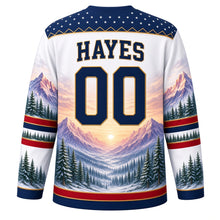 Load image into Gallery viewer, USA Patriotic Rocky Mountain Majesty Hockey Jersey in Glacier White, back view with your name and number – a decorative yoke of tiny white stars on navy edged with a thin gold mountain-ridge zigzag line yoke, matching sleeve and hem bands