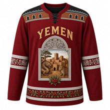 Load image into Gallery viewer, Yemen Original Hockey Jersey in Dragon's Blood Crimson, front view – ornate qamariya window crest with Shibam tower houses and dragon's blood tree, gypsum-frieze yoke, detailed artwork, custom name and number