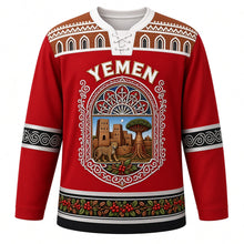 Load image into Gallery viewer, Yemen Original Hockey Jersey in Mocha Red, front view – ornate qamariya window crest with Shibam tower houses and dragon's blood tree, gypsum-frieze yoke, detailed artwork, custom name and number