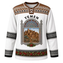 Load image into Gallery viewer, Yemen Original Hockey Jersey in Gypsum White, front view – ornate qamariya window crest with Shibam tower houses and dragon's blood tree, gypsum-frieze yoke, detailed artwork, custom name and number